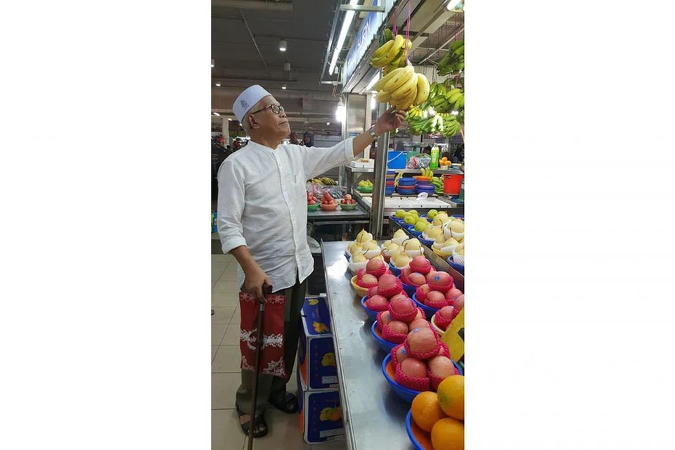 SAMA-SAMA BERBELANJA: Haji Mohd Sharip Haji Ahmad memilih beberapa jenis buah-buahan yang bakal disajikan sebagai pencuci mulut kepada tetamu di rumah terbuka anaknya, Cik Aizah. - Foto BH oleh SRI AFIQAH HAMIR