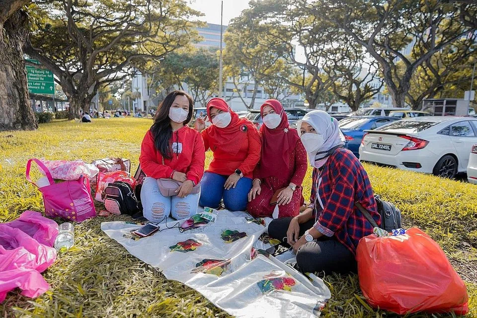 NIKMATI SUASANA SAMBUTAN HARI KEBANGSAAN: (Dari kiri) Pembantu rumah dan rakan-rakan sekampung dari Indonesia, Cik Tika, 38 tahun, Cik Amalia, 40 tahun, Cik Rossyta, 39 tahun dan Cik Yati, 40 tahun, duduk berdekatan padang di sebelah WGS untuk menyaksikan kemeriahan sambutan Hari Kebangsaan di WGS tengahari semalam.