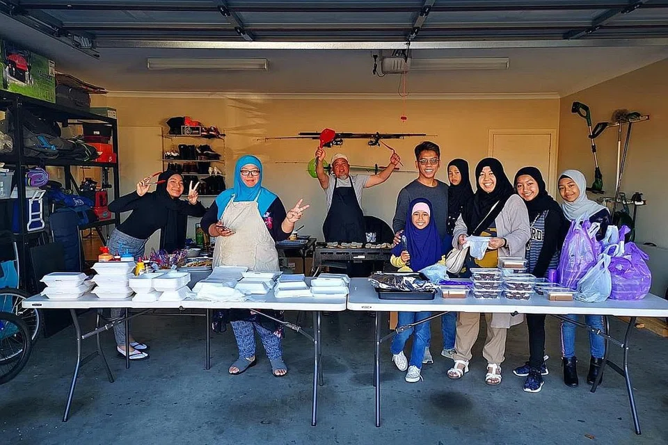 BAZAR MINI: Qamar Baba (lima dari kanan, sedang mengendong anaknya) bersama keluarga dan kenalan mengendalikan 'bazar mini' di pekarangan rumah mereka di Melbourne.- Foto ihsan QAMAR BABA