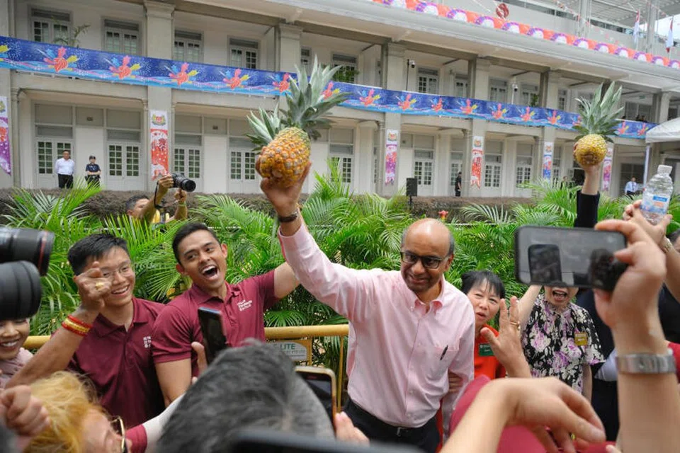 DEMI MASYARAKAT: Calon presiden, Encik Tharman Shanmugaratnam, memegang simbol kempennya, buah nanas, sambil menyambut penyokongnya pada Hari Penamaan Calon di ibu pejabat Persatuan Rakyat pada Selasa.