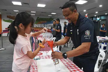 SUMBANG KEPADA MASYARAKAT: Fandi Ahmad (kanan) mengagihkan sanitiser tangan kepada seorang kanak-kanak di Our Tampines Hub kelmarin.- Foto BH oleh KHALID BABA