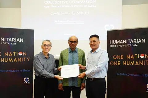 Presiden Dewan Perniagaan dan Perusahaan Melayu Singapura (DPPMS), Encik Abu Bakar Mohd Nor (kanan), menyerahkan cek kepada Duta Kelana dan pengerusi Humanity Matters, Encik Ong Keng Yong (kiri), bagi membantu warga di Gaza pada 10 Mac. Majlis tersebut turut dihadiri Presiden Tharman Shanmugaratnam (tengah).