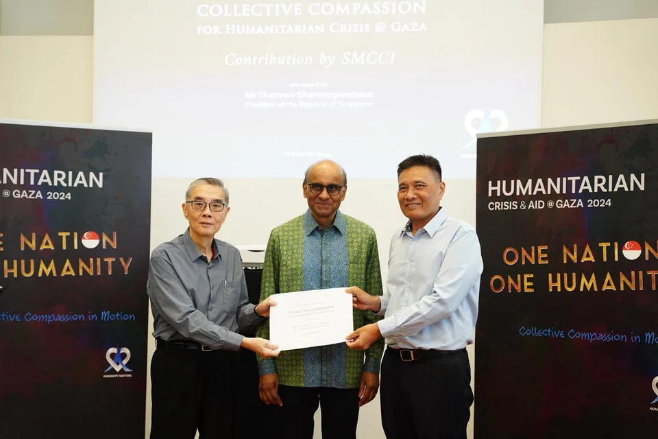 Presiden Dewan Perniagaan dan Perusahaan Melayu Singapura (DPPMS), Encik Abu Bakar Mohd Nor (kanan), menyerahkan cek kepada Duta Kelana dan pengerusi Humanity Matters, Encik Ong Keng Yong (kiri), bagi membantu warga di Gaza pada 10 Mac. Majlis tersebut turut dihadiri Presiden Tharman Shanmugaratnam (tengah).