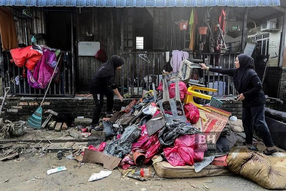 SUDAH REDA: Penduduk membersihkan kawasan rumahnya yang dilanda banjir di Kampung Durian Mentangau, Dungun. - Foto NSTP
