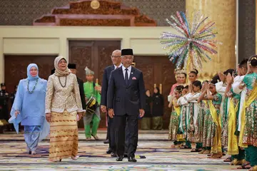 SAMBUTAN MEWAH: Presiden Halimah Yacob (dua dari kiri) diiringi Sultan Abdullah Ahmad Shah (tengah), Raja Permaisuri Agong Tunku Azizah Aminah Iskandariah (paling kiri) dan suami Puan Halimah, Encik Abdullah Alhabshee (belakang Agong) sebelum memasuki dewan bagi Majlis Santapan Negara. Mereka disambut dengan alunan kompang dan barisan penari kanak-kanak. - Foto ST