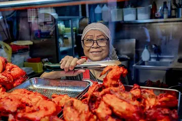CUBA MENGEKALKAN HARGA: Cik Jumaiah, pemilik gerai makanan Maya Pesona Chicken Rice, berharap dapat terus mengekalkan harga yang rendah supaya orang ramai dapat terus menikmati makanannya. - Foto-foto BH oleh NUR DIYANA TAHA