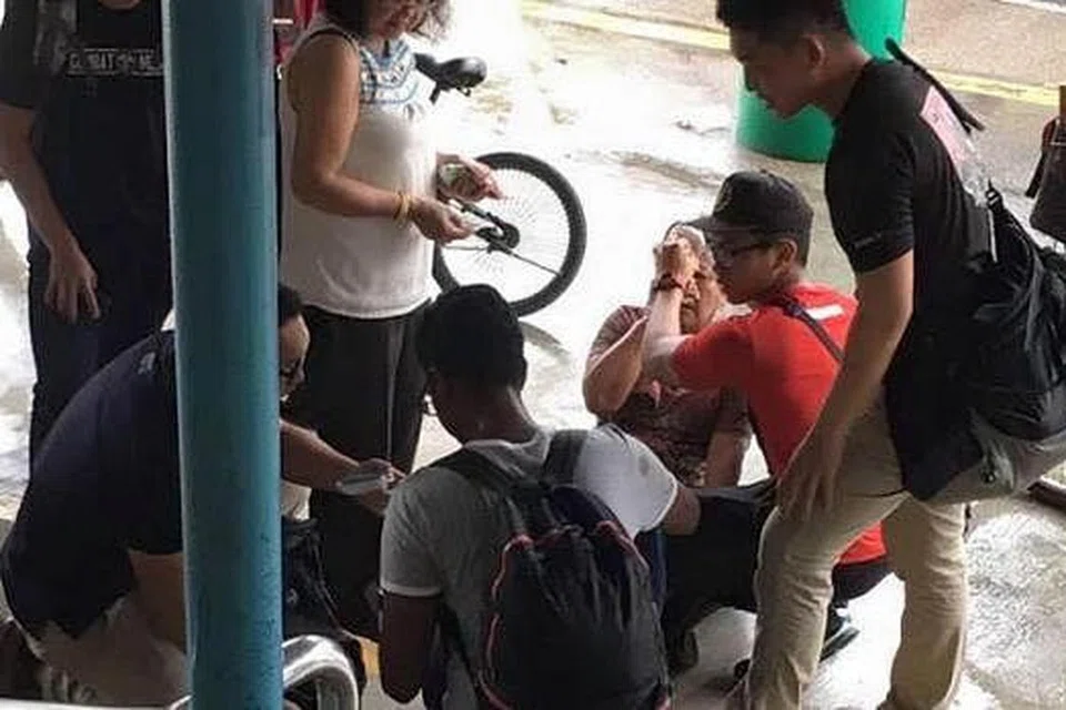Wanita tua yang terjatuh dekat MRT Yishun dibantu kakitangan SAF yang tidak bertugas. Gambar ASHRAF ALI KHAN