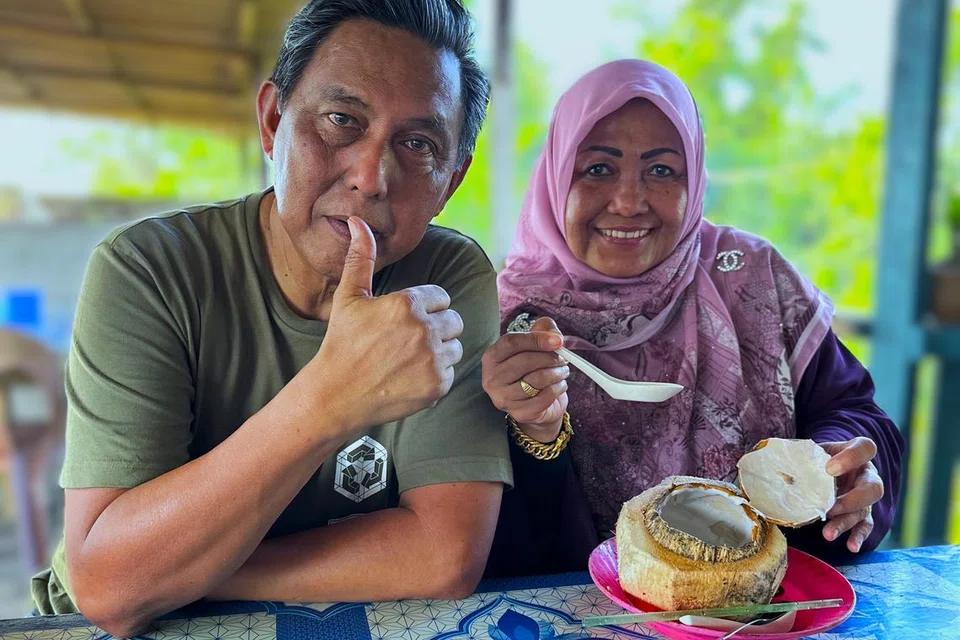 Encik Sahari (kiri) bersama isterinya, Cik Hamimah Lazim, menikmati kelapa bakar yang merupakan makanan popular di Tuaran, Kota Kinabalu.