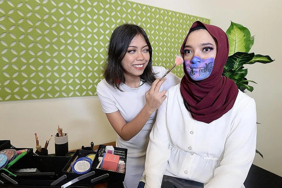 SOLEKAN KESAN KHAS: Jurusolek bebas, Cik Athirah Khairwan, melakukan solekan kesan khas ke atas wartawan, Cik Natasha Mustafa, yang berupa pelitup siap dengan ikon-ikon Singapura khas untuk 'The BM Show' sempena Hari Kebangsaan Singapura ke-55. - Foto BH oleh NUR HUMAIRA SAJAT
