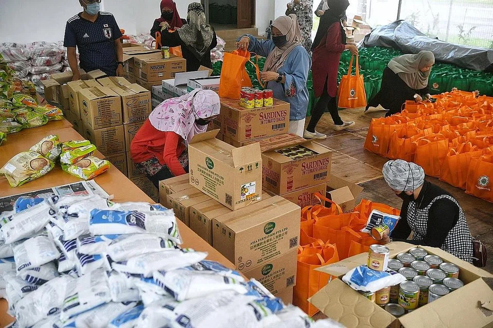 SEBAR KECERIAAN: Habuan seperti tepung, biskut, makanan tin dan beras, telah dibungkus dan diagihkan kepada seramai 400 penerima bantuan menerusi usaha Ramadan Charity Basket anjuran SimpyIslam.sg. - Foto BH oleh KUA CHEE SIONG