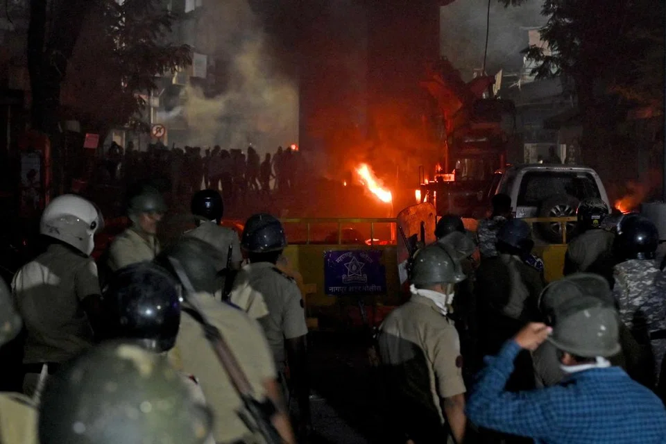 Anggota polis berkawal ketika beberapa kenderaan terbakar susulan pertempuran yang tercetus akibat tuntutan untuk merobohkan makam maharaja Mughal Aurangzeb, di Nagpur, India, pada 17 Mac 2025.