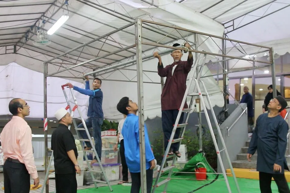 MENGATUR PERSIAPAN: Di Masjid Al-Mukminin, para relawan berganding bahu memasang khemah bagi acara korban. - Foto BH oleh PUTRI MARDHIYAH YAZID