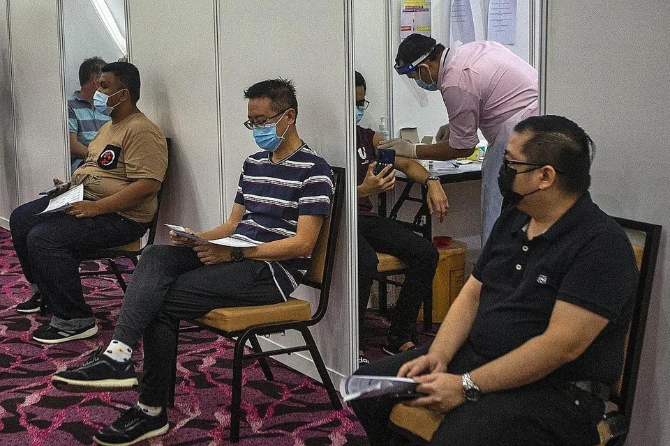 TUNGGU GILIRAN DISUNTIK: Beberapa penduduk di Shah Alam, berdekatan ibu kota Kuala Lumpur, sedang menunggu giliran untuk menerima suntikan vaksin Covid-19 sedang Malaysia terus mencatat kenaikan kes baru jangkitan koronavirus itu. - Foto EPA-EFE