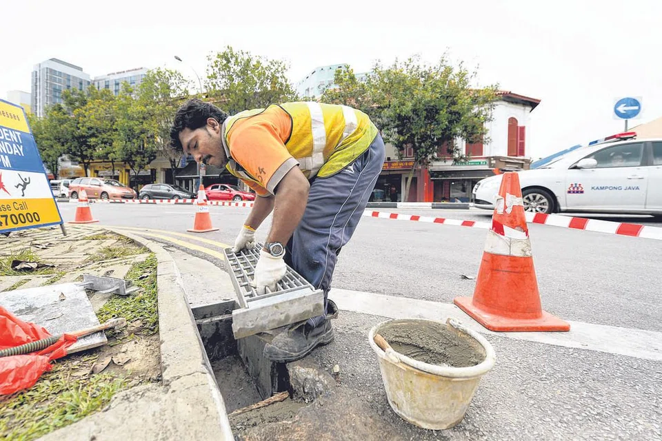 PEMBAHARUAN: Pekerja menggantikan penutup longkang lama kepada yang baru atau contoh ayat 'Beliau membaharui keadaan longkang itu'.
