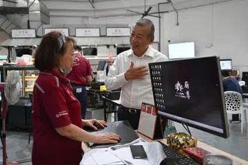 DEKATI MASYARAKAT: Usahawan Encik George Goh (kanan), yang berhasrat bertanding dalam Pilihan Raya Presiden, mengunjungi perusahaan sosial Dignity Kitchen pada Khamis, dan turut membantu membungkus makanan tengah hari untuk warga emas.