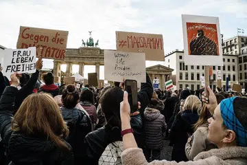 BANTAHAN MEREBAK: Penunjuk perasaan memegang plakad semasa perhimpunan membantah kematian Cik Mahsa Amini, di hadapan Gerbang Brandenburg di Berlin, Jerman, 28 September 2022. Cik Mahsa seorang wanita Iran berusia 22 tahun, telah ditangkap polis pencegah maksiat di Tehran pada 13 September oleh polis. Beliau koma semasa dalam tahanan polis dan diisytiharkan mati pada 16 September. - Foto EPA-EFE