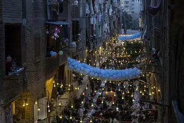 Orang ramai di daerah Matareya berkumpul untuk berbuka puasa beramai-ramai semasa bulan suci Ramadan di Kahirah, Mesir, pada 5 Mac 2026. Meja panjang untuk berbuka puasa beramai-ramai merupakan acara tahunan di Mesir yang bermula lebih sedekad lalu di kawasan kejiranan Al-Matareya.