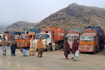 Orang ramai berdiri di sebelah lori yang sarat dengan bekalan di lintasan sempadan Torkham selepas penutupan sempadan antara Pakistan dan Afghanistan pada 3 Mac 2025. 