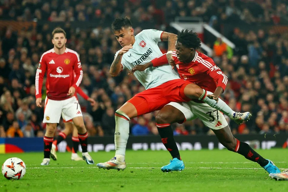 Pemain barisan pertahanan FC Twente, Mees Hilgers (kiri) sedang berebut bola dengan pemain tengah Manchester United, Kobbie Mainoo semasa perlawanan pembukaan Liga Europa  pada 25 September di Manchester, England