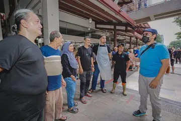 Pemilik laman geylangserai.shop, Encik Mohamed Fahmi Abdullah (kanan), dan ketua pemandu pasukannya, Encik Mohd Nizam Abdullah (kiri), berinteraksi bersama peniaga di Pasar Geylang Serai pada 25 Julai.