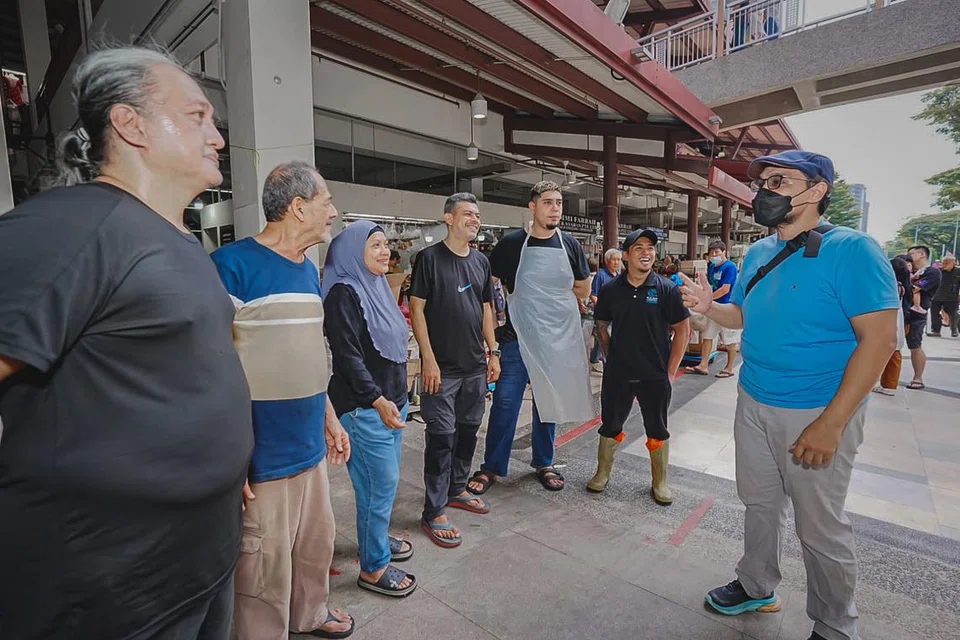 Pemilik laman geylangserai.shop, Encik Mohamed Fahmi Abdullah (kanan), dan ketua pemandu pasukannya, Encik Mohd Nizam Abdullah (kiri), berinteraksi bersama peniaga di Pasar Geylang Serai pada 25 Julai.