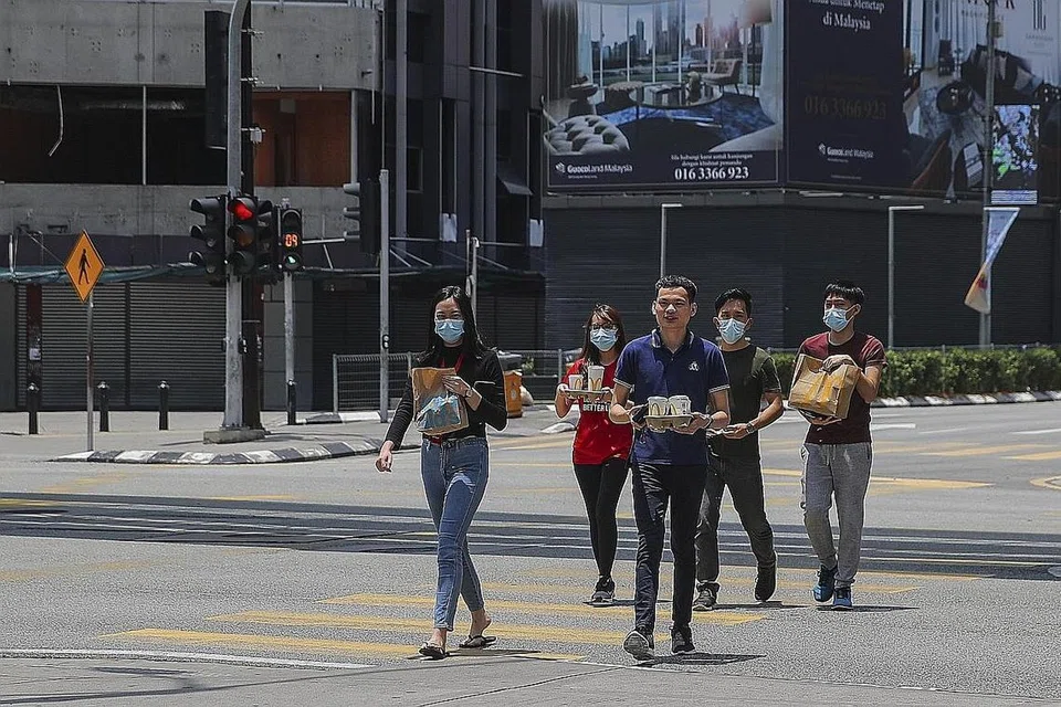 BUNGKUS MAKANAN: Orang ramai membungkus makanan demi mematuhi Perintah Kawalan Pergerakan yang mula berkuatkuasa kelmarin. - Foto EPA-EFE