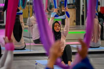 Anggota wanita berlatih yoga udara dalam sebuah sesi di pusat gimnasium khusus wanita di Banda Aceh pada 19 Julai 2025 sedang pemerintah Jakarta mewajibkan  senaman kecergasan setiap hari Jumaat untuk penjawat awam.