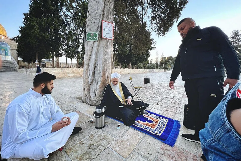  'MENGETEH' DI BAWAH POKOK: (Dari kiri) Encik Abdul Rahman, pelancong dari Manchester; imam masjid, Sheikh Ali Omar Yacoub Abbasi dan penderma teh, Encik Abu Ibrahim.- Foto BH oleh HARITH MUSTAFFA 