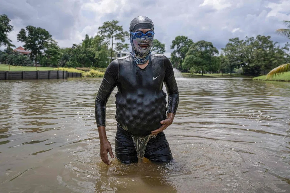 Mantan penyelam Tentera Laut Diraja Malaysia, Encik Sumadi Ibrahim, 51 tahun, memungut bola-bola golf yang tenggelam dan memasukkan ke dalam baju selamnya di tasik padang golf di Shah Alam.