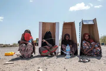 DI BAWAH TERIK MENTARI: Sekumpulan wanita dilihat duduk dengan beralaskan kadbod dengan jenama Pesuruhjaya Tinggi Bangsa-Bangsa Bersatu untuk Pelarian (UNHCR) sementara menunggu untuk berdaftar dengan pihak berkuasa di halaman Hotel Agda di kota Semera di Ethiopia, pada 14 Februari lalu, bagi mendapatkan bantuan kemanusiaan. - Foto AFP