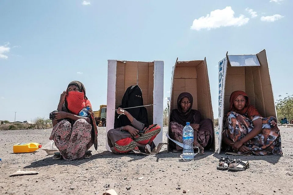 DI BAWAH TERIK MENTARI: Sekumpulan wanita dilihat duduk dengan beralaskan kadbod dengan jenama Pesuruhjaya Tinggi Bangsa-Bangsa Bersatu untuk Pelarian (UNHCR) sementara menunggu untuk berdaftar dengan pihak berkuasa di halaman Hotel Agda di kota Semera di Ethiopia, pada 14 Februari lalu, bagi mendapatkan bantuan kemanusiaan. - Foto AFP