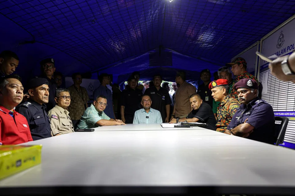 Perdana Menteri Malaysia, Datuk Seri Anwar Ibrahim (tengah), mendengar penerangan daripada pihak berkuasa ketika meninjau tapak kebakaran akibat kebocoran saluran paip gas di pusat operasi Polis Diraja Malaysia (PDRM) dan Jabatan Bomba dan Penyelamat Malaysia (JBPM) di Taman Putra Harmoni.