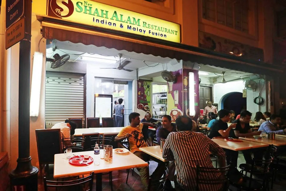 TERUSKAN NIAGA: Seorang pelanggan dilihat terbongkok dengan kepalanya terletak atas meja di tepi (kiri), namun pekerja kedai perata New Shah Alam tidak mengejut lelaki itu dan meneruskan tugas mereka. - Foto BH oleh KELVIN CHNG
