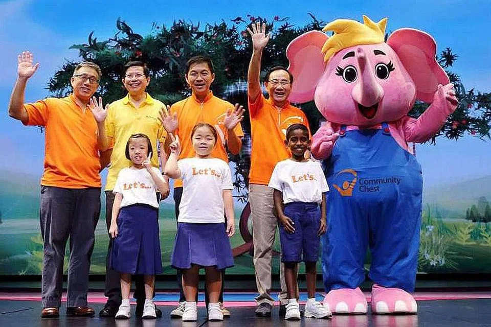 GALAK BERBUAT BAIK: Pelajar Sekolah Grace Orchard dengan (dari kiri) pengerusi jawatankuasa penganjur Hari Sharity 2015, Encik Chew Kwee San; Ketua Pegawai Eksekutif Resorts World Sentosa, Encik Tan Hee Teck; Menteri Pembangunan Sosial dan Keluarga, Encik Tan Chuan-Jin; pengerusi Dana Masyarakat, Encik Phillip Tan; dan maskot Sharity di Panggung World Resorts pada 3 Oktober 2015. - Foto NCSS