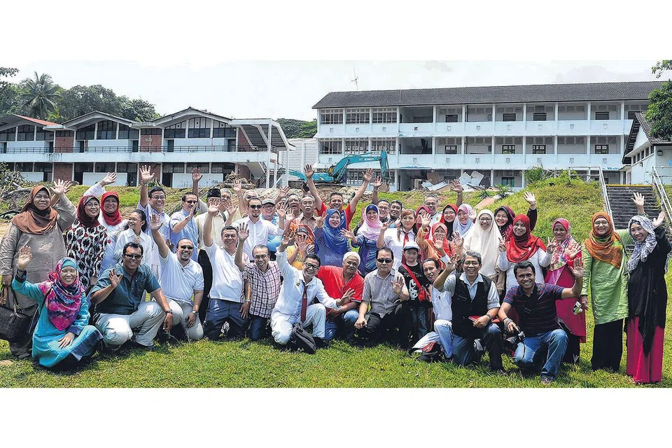 KENANGAN DI SEKOLAH LAMA: Sekumpulan bekas pelajar Sekolah Menengah Sang Nila Utama, termasuk mantan Anggota Parlimen Yatiman Yusof, merakam gambar kenangan di depan sekolah mereka pada 8 September 2014 sebelum bangunan itu dirobohkan. - Foto fail