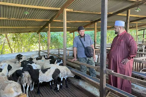 KEUTAMAAN MEMBANTU: Pengasas IbadahSG, Ustaz Firdaus Masruhen (kanan), bersama seorang penjaga ladang kambing berada di kandang kambing IbadahSG di Jawa Timur, dan prihatin terhadap warga susah di negara tersebut. 
