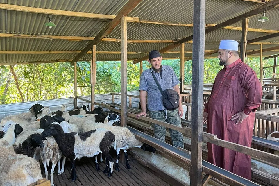 KEUTAMAAN MEMBANTU: Pengasas IbadahSG, Ustaz Firdaus Masruhen (kanan), bersama seorang penjaga ladang kambing berada di kandang kambing IbadahSG di Jawa Timur, dan prihatin terhadap warga susah di negara tersebut. 