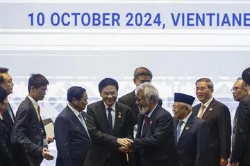 Perdana Menteri Singapura, Encik Lawrence Wong (dua dari kiri), menyapa Perdana Menteri Timor Timur, Encik Xanana Gusmao, dengan  diperhatikan beberapa pemimpin lain, antaranya Perdana Menteri Vietnam, Encik Pham Minh Chinh (kiri);  Perdana Menteri China, Encik Li Qiang (dua dari kanan); dan Perdana Menteri Malaysia, Datuk Seri Anwar Ibrahim (kanan); semasa Sidang Puncak  Asean Ditambah Tige ke-27 di Pusat Konvensyen Nasional di Vientiane, Laos, pada 10 Oktober. 