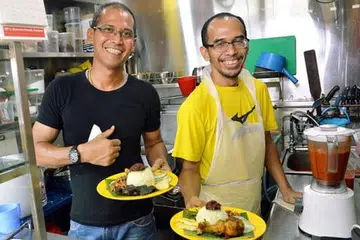 MULA LEMBARAN BARU: Selepas 14 tahun meninggalkan Singapura, kini bekas pengurus besar di sebuah syarikat berbilang negara, Encik Aminurashed (kanan), mengambil keputusan memulakan perniagaannya sendiri dengan menjual nasi lemak di warung pertamanya. Beliau kini dibantu rakannya, Encik Mohammad Noor (kiri). - Foto-foto KHALID BABA 