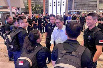 SEDIA HULUR BANTUAN: Dr Faishal (tengah) beramah dengan anggota pasukan respons awal SCDF di lapangan terbang Changi sebelum mereka berlepas. Turut bersama beliau ialah Pesuruhjaya SCDF, Komander Eric Yap (di kanan Dr Faishal), dan ketua kontinjen, LTC Lok Wee Keong (paling kanan). - Foto SCDF