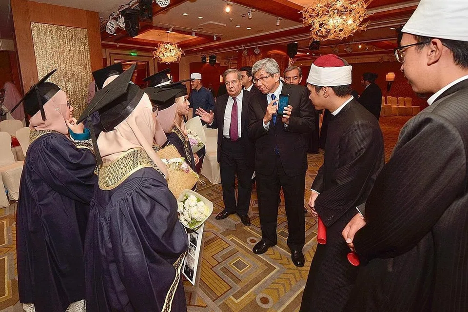 BANGUNKAN BAKAT KEAGAMAAN: Mantan Menteri Bertanggungjawab bagi Ehwal Masyarakat Islam, Dr Yaacob Ibrahim (tiga dari kanan) berinteraksi dengan lulusan Universiti Al-Azhar di majlis penyampaian ijazah di Mesir pada 2014. - Foto MUIS.