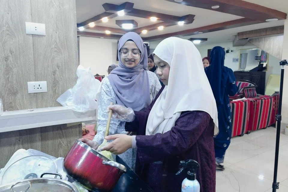 Pelajar Singapura Tahun 4 di Universiti Yarmouk, Jordan, (dari kiri) Cik Nazeefah Hishmah Muhammed Thariq dan Cik Nur Khalisha Shafie membungkus pek makanan untuk dibawa pulang dari majlis Perjumpaan Hari Raya pada 22 Mac.