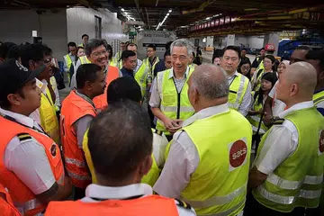 BELA PEKERJA: Gambar diambil pada 14 Februari 2020 semasa Perdana Menteri Lee Hsien Loong (tengah) mengadakan lawatan ke Terminal 3 Lapangan Terbang Changi dan bertemu pekerja pengendali beg. - Foto fail