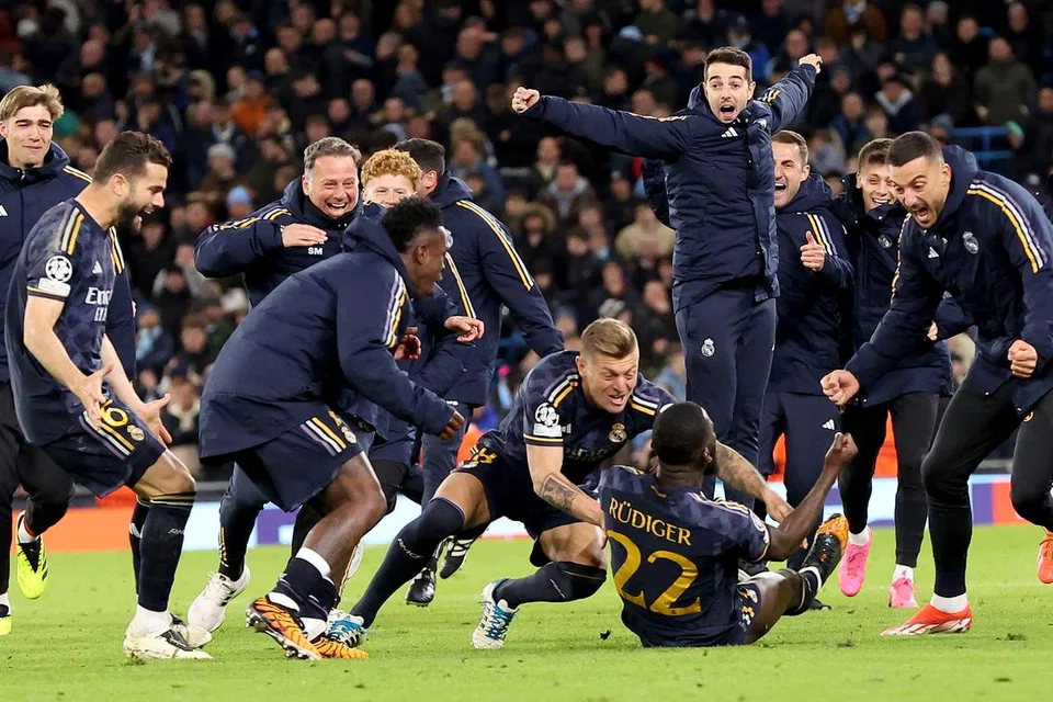 Pemain Real Madrid menyerbu bek tengah Antonio Rudiger (nombor 22) selepas beliau menjaringkan gol semasa sepakan penalti penentu yang memastikan mereka mara ke separuh akhir Liga Juara-Juara.