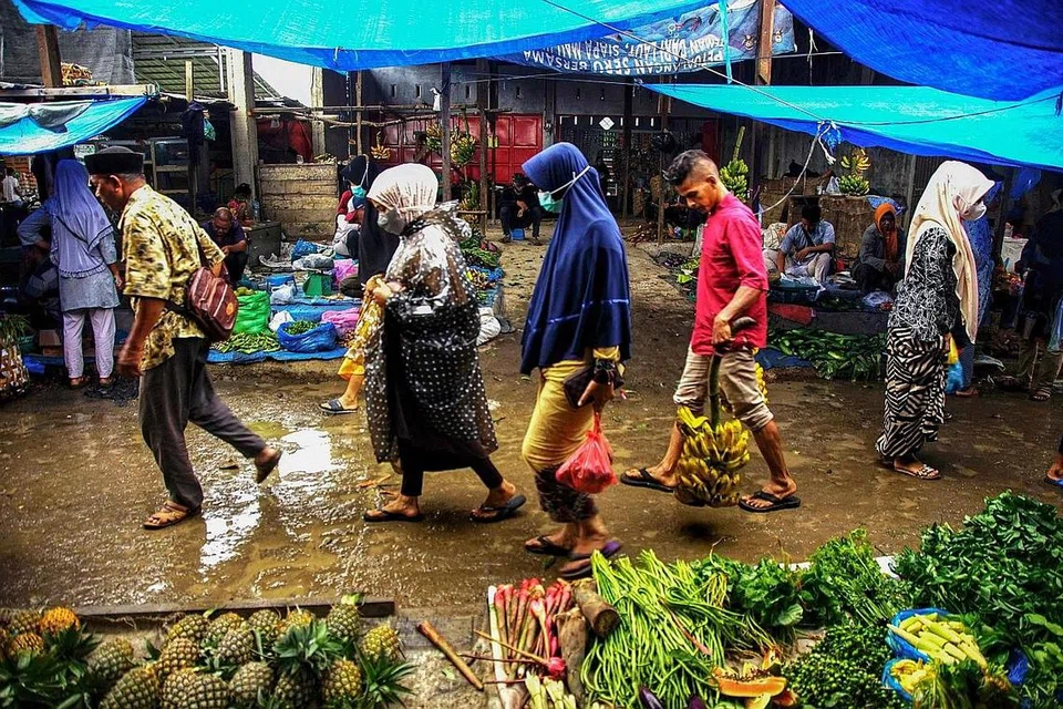 TERDEDAH RISIKO JANGKITAN: Pengunjung membeli barang dapur di pasar tempatan di Lhokseumawe, Aceh. Ada di antara pembeli dan penjual yang tidak memakai pelitup. - AFP