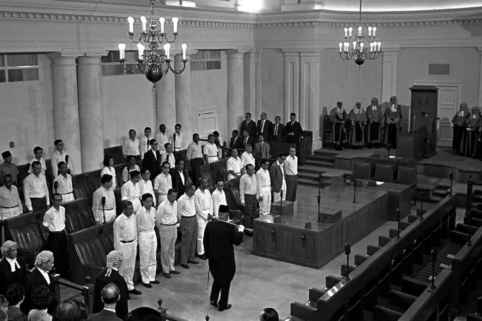 SESI PARLIMEN BERLANGSUNG: Bentara Cokmar Encik Mahmood Abdul Wahab membawa cokmar semasa memimpin perarakan Speaker di pembukaan parlimen pertama Singapura pada 8 Disember 1965.
