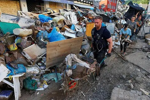 BERAT SAMA DIPIKUL: Seorang anggota polis dan sukarelawan membersihkan sebuah kawasan perumahan, Bad Muenstereifel, yang teruk dilanda hujan lebat dan banjir minggu lalu. - Foto REUTERS