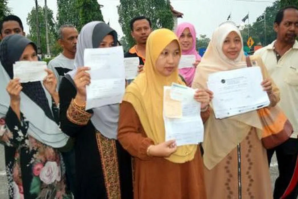 BUAT LAPORAN POLIS: Cik Hasnida (tiga kanan) bersama mangsa lain menunjukkan laporan polis terhadap syarikat pakej umrah yang didakwa gagal menunaikan janji. - Foto NSTP