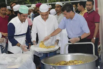 SAHUR BERSAMA: Menteri Negara Kanan Pertahanan, Encik Heng Chee How, kelihatan sedang menyenduk nasi di dulang yang dibawa ketua pegawai eksekutif dan pengasas syarikat Mini Environment Services (MES) Group, Encik Mohamed Abdul Jaleel, semasa berkunjung ke dormitori The Leo, di Kaki Bukit awal pagi semalam. - Foto MES