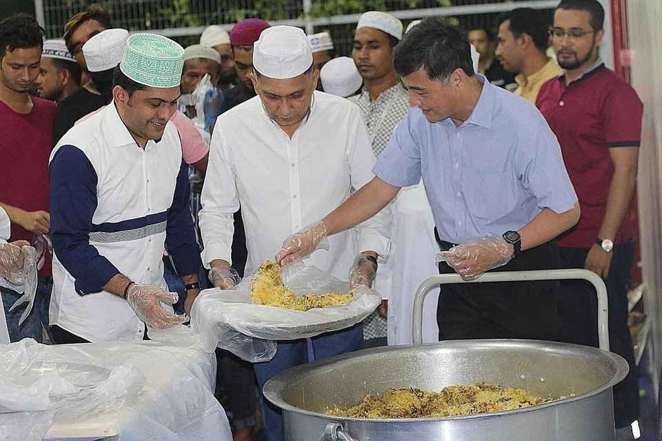 SAHUR BERSAMA: Menteri Negara Kanan Pertahanan, Encik Heng Chee How, kelihatan sedang menyenduk nasi di dulang yang dibawa ketua pegawai eksekutif dan pengasas syarikat Mini Environment Services (MES) Group, Encik Mohamed Abdul Jaleel, semasa berkunjung ke dormitori The Leo, di Kaki Bukit awal pagi semalam. - Foto MES